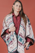 Woman wearing a patterned poncho against a red background
